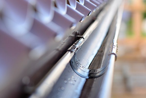 Close up of a metal gutter on a roof, with a blurred background