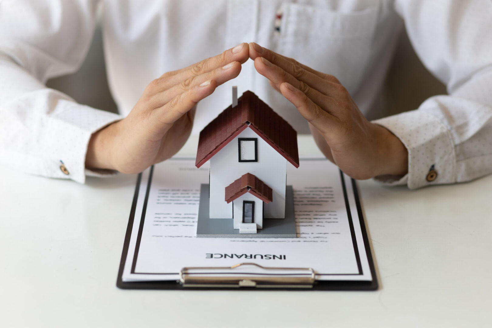 Woman holding a small house on top of a clipboard with the words "Insurance" written on it