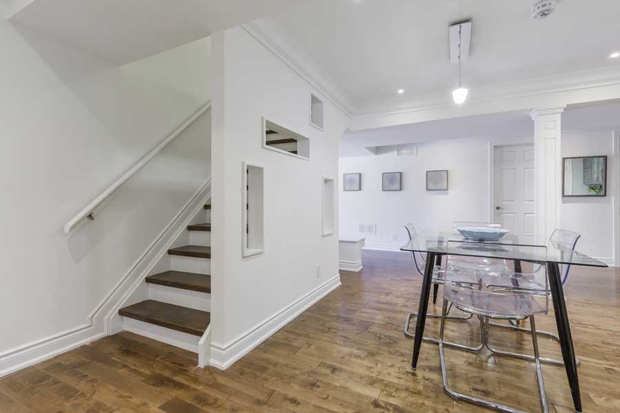 Dining room with a glass table and chairs, a bowl on the table, a staircase with a railing