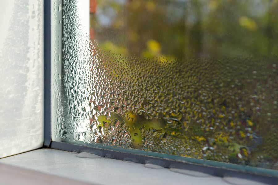Close up of a window with water droplets on it, set against a blurred background