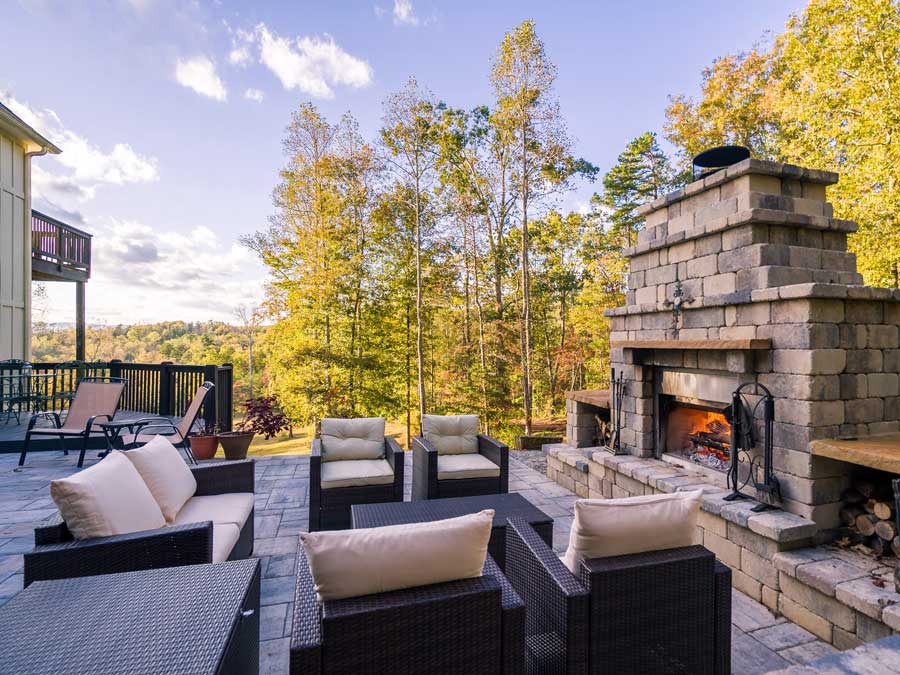 Patio with wicker furniture, including sofas, chairs, and tables, arranged around a fireplace