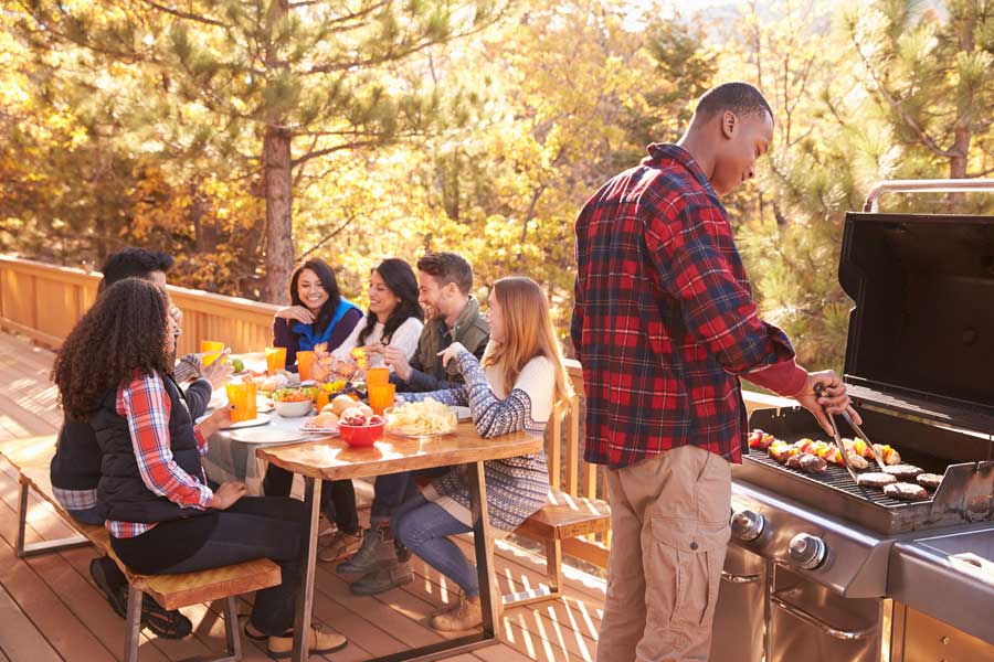 Group of people gathered around a table on a deck, enjoying a meal together