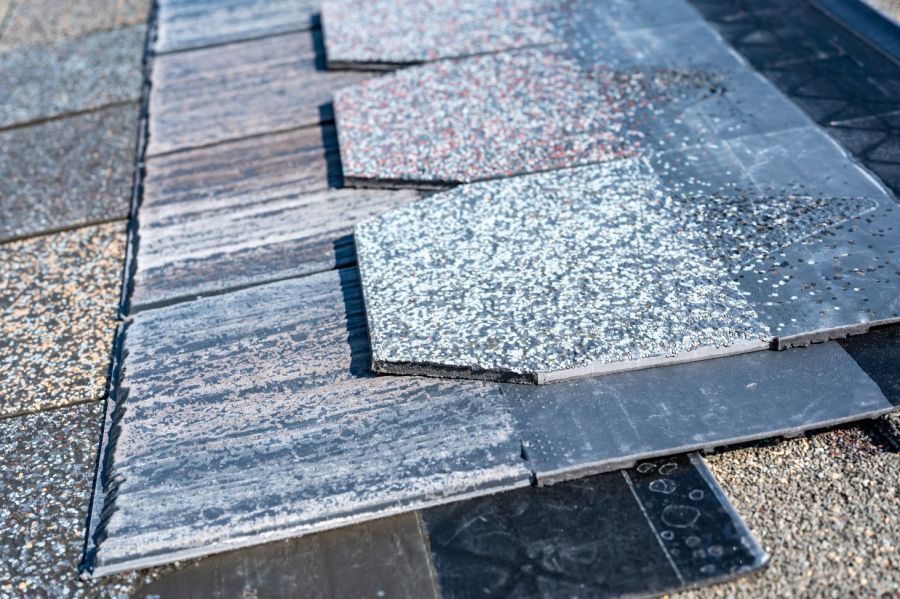 Close up of a roof with a lot of shingles on it, and a black object on the ground