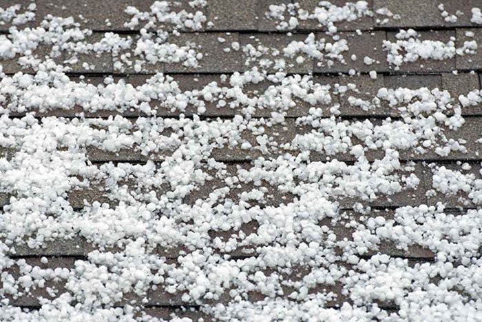 Roof covered in hail, with the white hail particles scattered across the surface