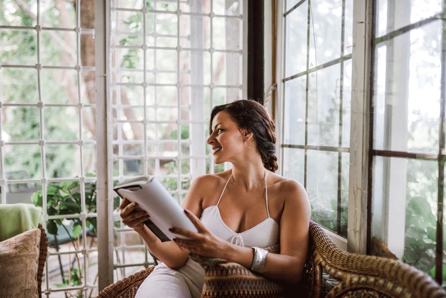 Woman sitting in a chair, as she reads a book