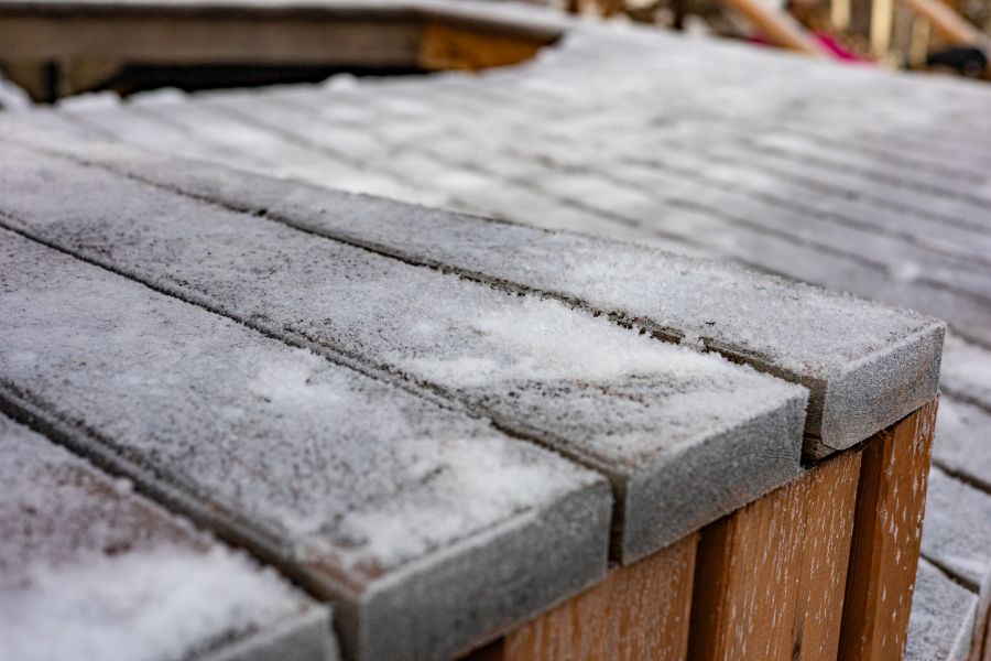 Wooden deck covered in snow, with a wooden fence in the background