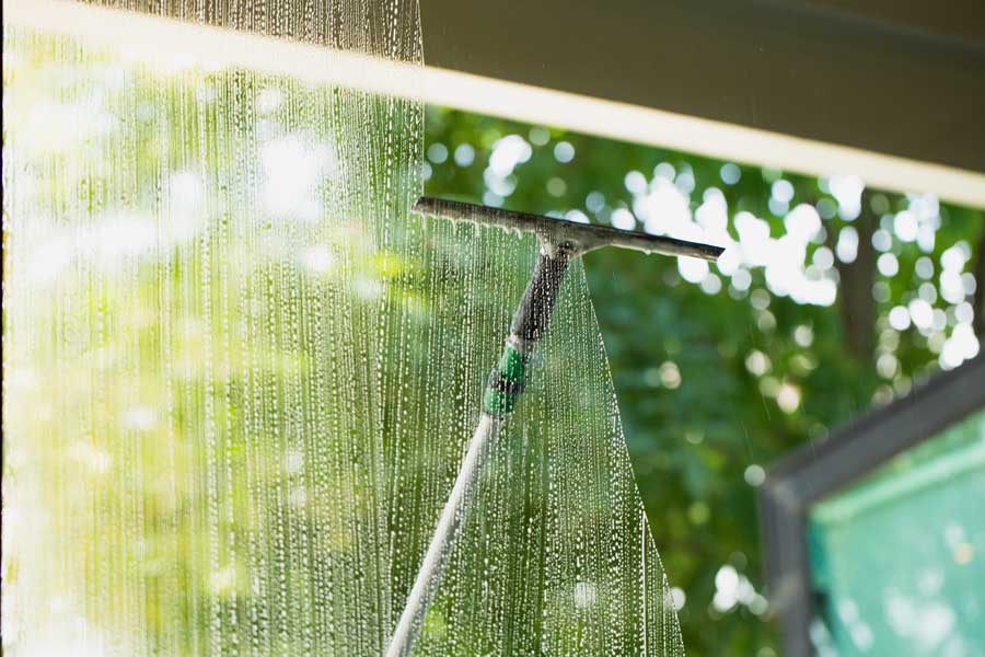 Window with a squeegee attached to it, spraying water onto the glass