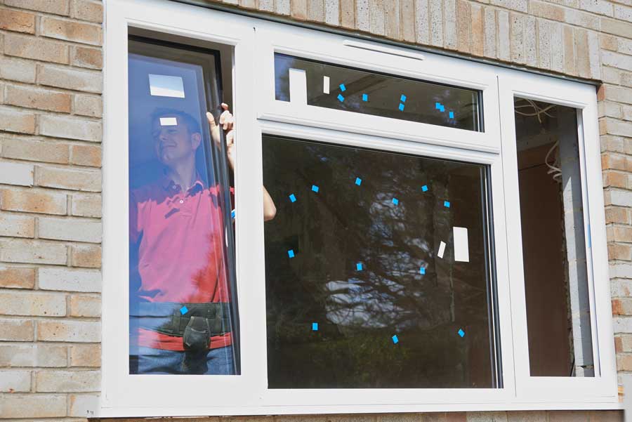 Man standing in front of a brick wall, holding a window with a glass pane