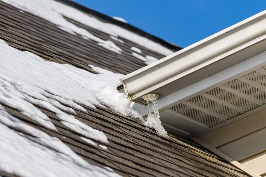 Roof of a house with snow on it and a gutter in the foreground