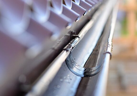 Close up of a metal gutter on a roof, with a blurred background