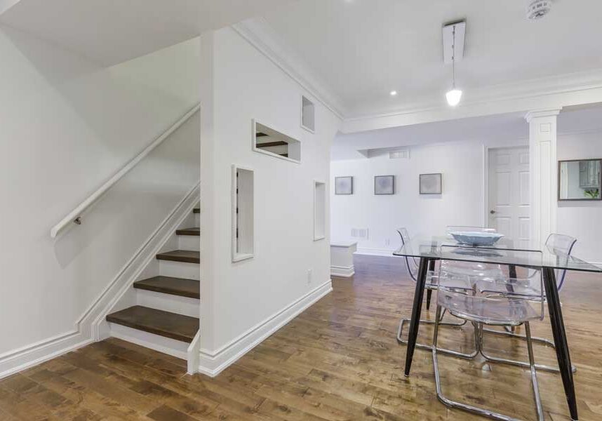 Dining room with a glass table and chairs, a bowl on the table, a staircase with a railing