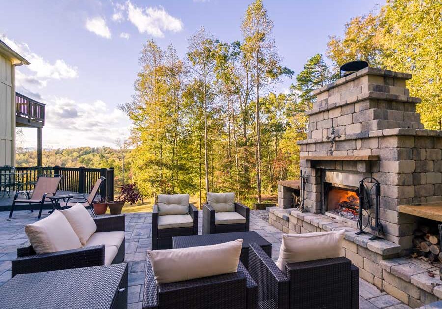 Patio with wicker furniture, including sofas, chairs, and tables, arranged around a fireplace