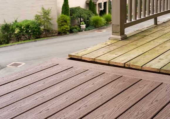 Wooden deck with a railing and a house in the background