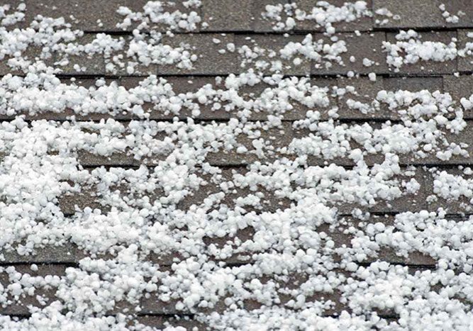 Roof covered in hail, with the white hail particles scattered across the surface