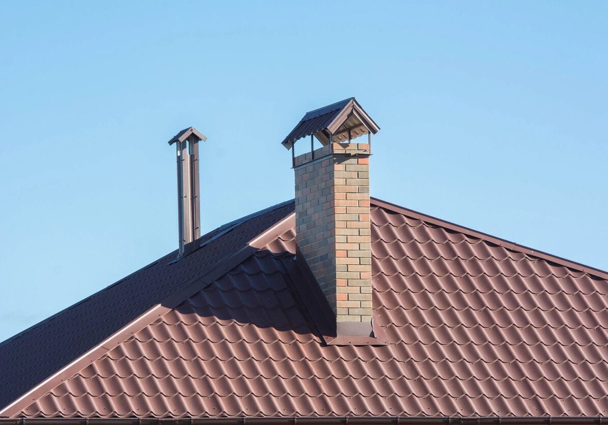 House with a metal roof and a chimney, with a clear blue sky in the background