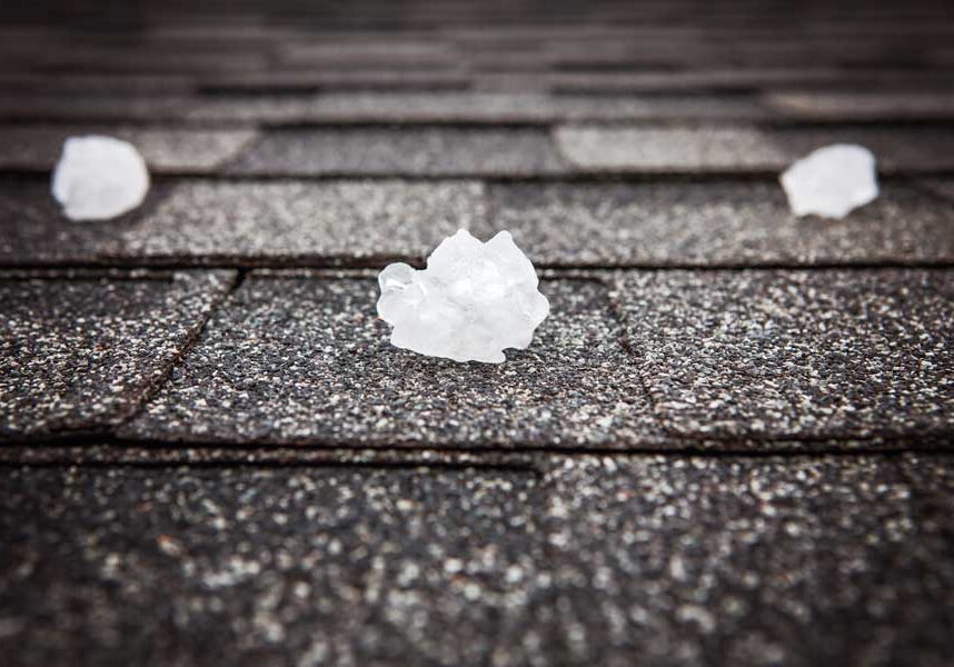 Roof of a house in with hail scattered across it, indicating that the roof is in need of repair