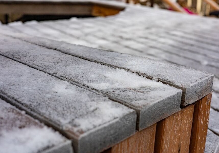 Wooden deck covered in snow, with a wooden fence in the background
