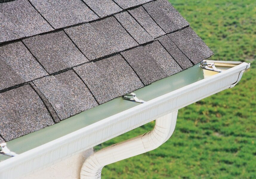 Roof of a house with a gutter running along the side of it, and a pipe running along it
