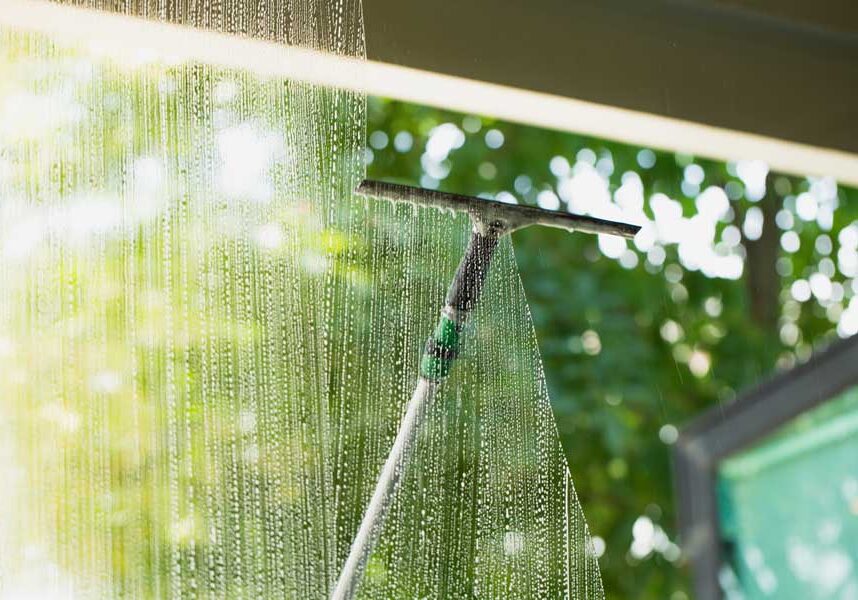 Window with a squeegee attached to it, spraying water onto the glass
