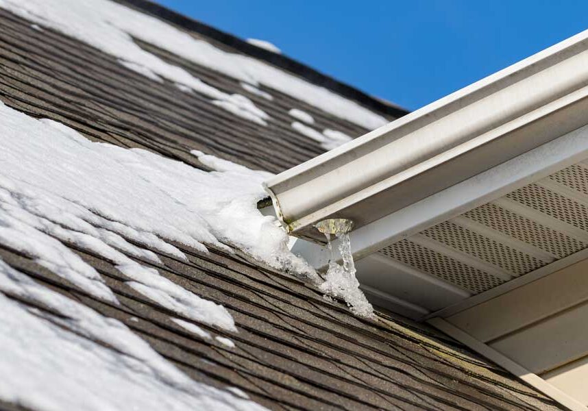 Roof of a house with snow on it and a gutter in the foreground